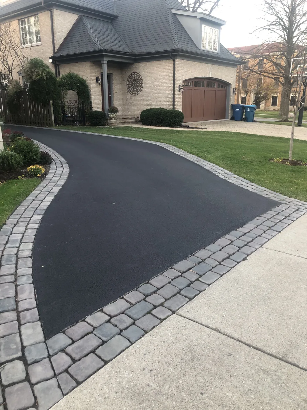 New asphalt driveway with a paver border beside a concrete sidewalk in Manotick, Ottawa